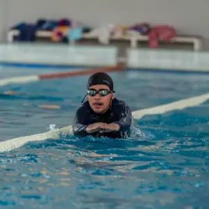joven nadando en piscina techada con lentes para agua